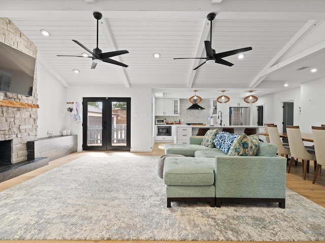 living room featuring lofted ceiling with beams, light wood-style flooring, french doors, and ceiling fan