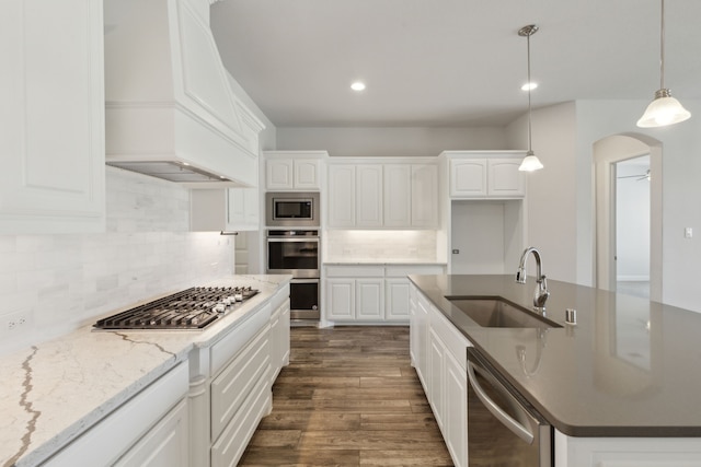 kitchen featuring custom exhaust hood, dark wood-style flooring, a sink, appliances with stainless steel finishes, and white cabinetry