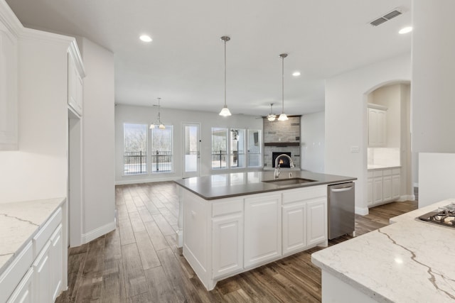 kitchen featuring visible vents, a sink, appliances with stainless steel finishes, open floor plan, and a large fireplace