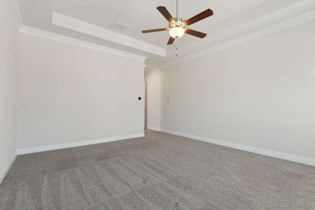 empty room with baseboards, visible vents, a tray ceiling, ornamental molding, and ceiling fan