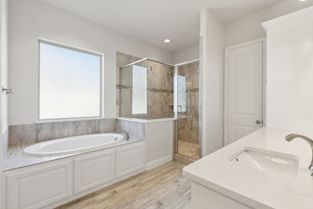 full bath with a bath, a shower stall, wood finished floors, and a sink