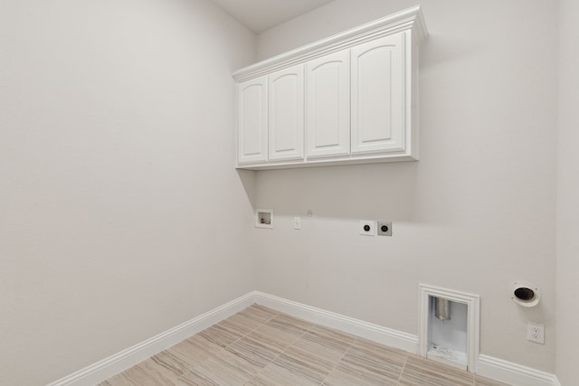 clothes washing area with electric dryer hookup, washer hookup, cabinet space, baseboards, and gas dryer hookup