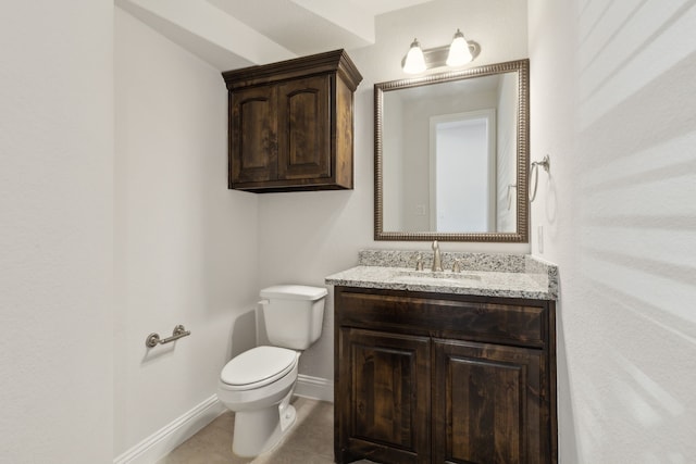 half bathroom with tile patterned flooring, toilet, vanity, and baseboards