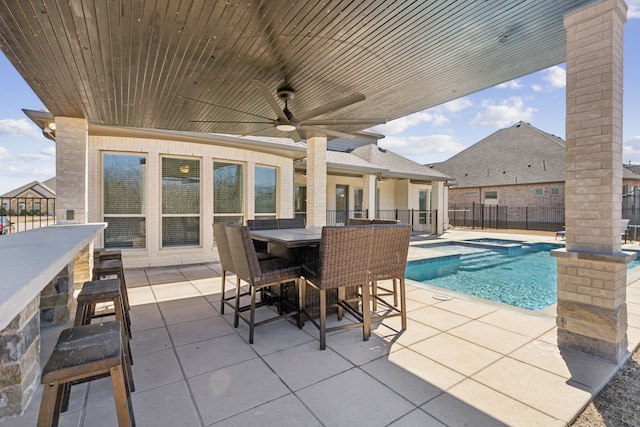 view of swimming pool featuring a patio, a ceiling fan, fence, outdoor dining area, and a large fireplace