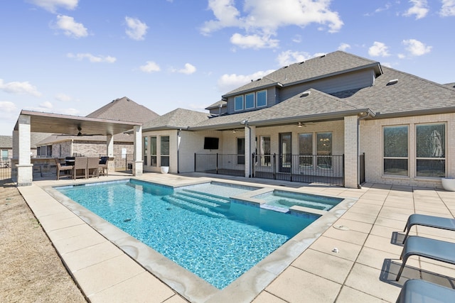 view of swimming pool featuring fence, a pool with connected hot tub, a ceiling fan, and a patio area