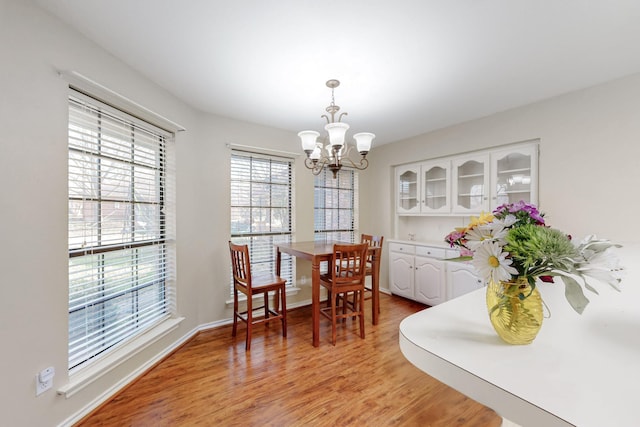 dining area featuring a wealth of natural light, baseboards, light wood-type flooring, and an inviting chandelier