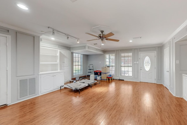 unfurnished room with light wood finished floors, visible vents, crown molding, a decorative wall, and a ceiling fan