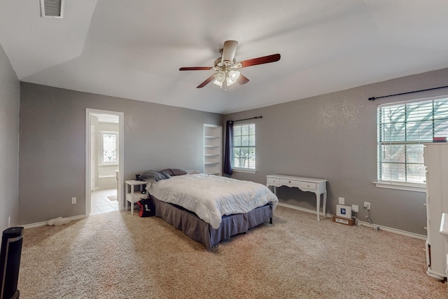 carpeted bedroom with visible vents, multiple windows, ensuite bath, and baseboards