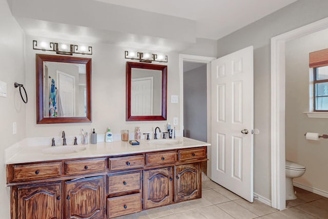 full bathroom with a sink, toilet, double vanity, and tile patterned floors