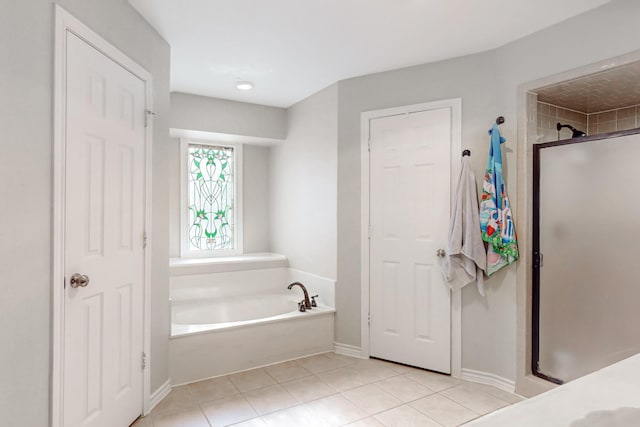 bathroom featuring tile patterned flooring, a shower stall, a garden tub, and baseboards