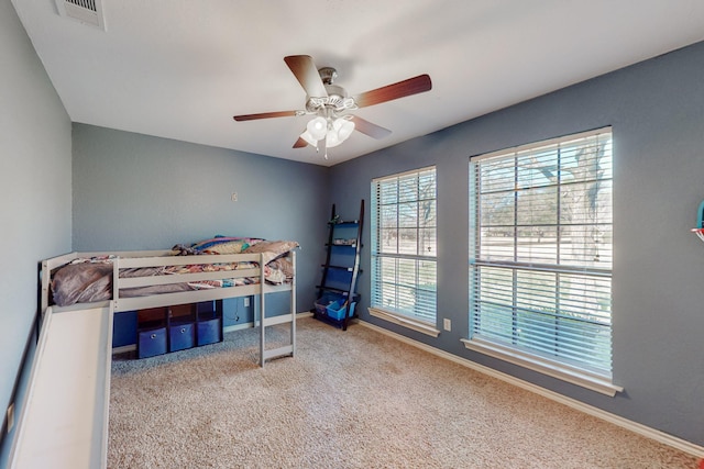 carpeted bedroom with visible vents, baseboards, and ceiling fan