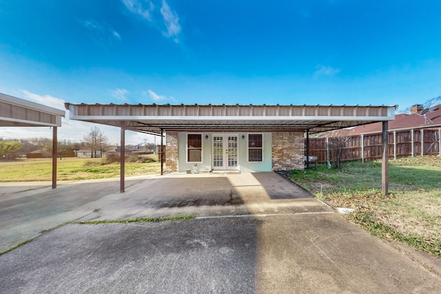 exterior space with brick siding, a yard, french doors, and fence