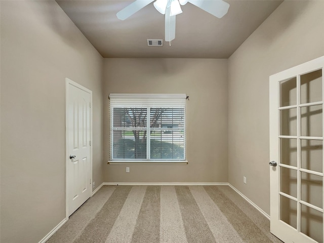 unfurnished room featuring baseboards, visible vents, a ceiling fan, and carpet