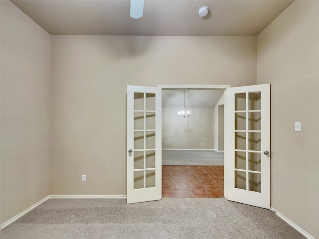 spare room with baseboards, carpet, ceiling fan with notable chandelier, french doors, and tile patterned floors