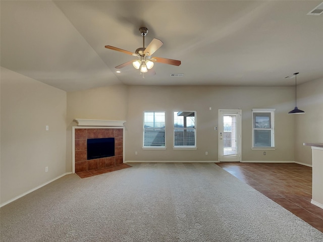 unfurnished living room with visible vents, carpet floors, a fireplace, tile patterned flooring, and ceiling fan