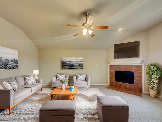 carpeted living area featuring lofted ceiling, a ceiling fan, baseboards, and a tile fireplace