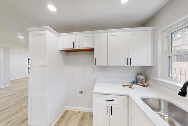 kitchen featuring light wood finished floors, recessed lighting, white cabinets, and a sink