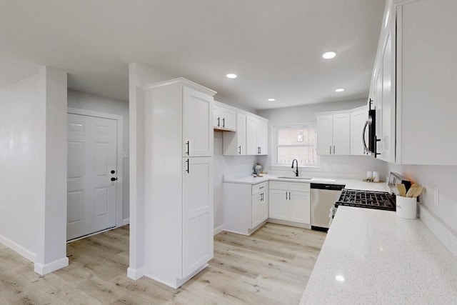 kitchen featuring light wood-style flooring, white cabinets, appliances with stainless steel finishes, and a sink