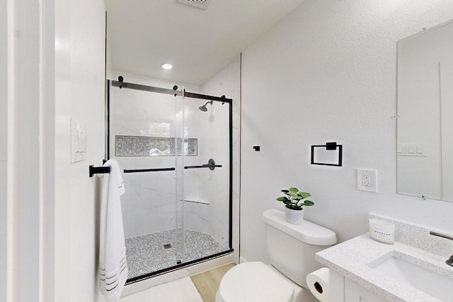 bathroom featuring vanity, a shower stall, toilet, and wood finished floors