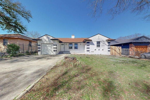 view of front of home with an attached garage, driveway, a front lawn, and fence