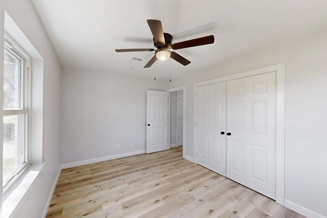 unfurnished bedroom featuring a ceiling fan, visible vents, wood finished floors, baseboards, and a closet