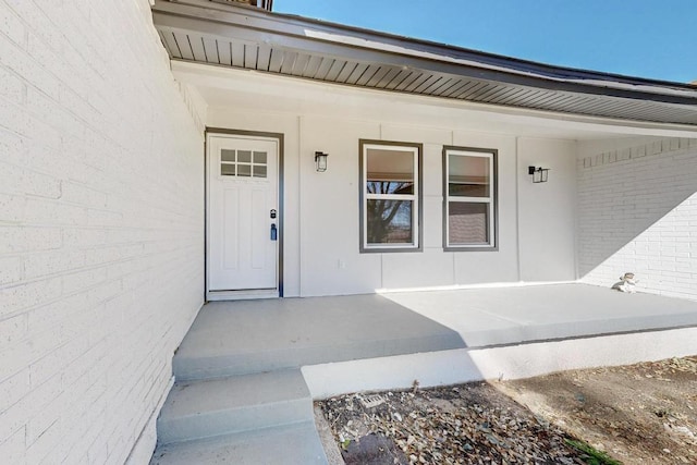 doorway to property featuring brick siding and covered porch