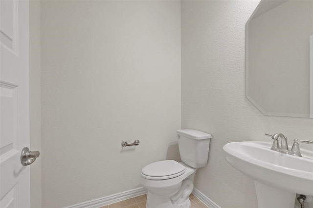 bathroom featuring a sink, toilet, baseboards, and tile patterned flooring