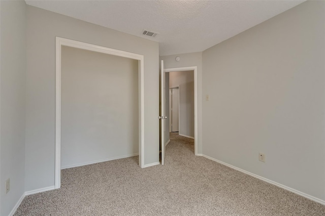 unfurnished bedroom with light carpet, baseboards, and a textured ceiling
