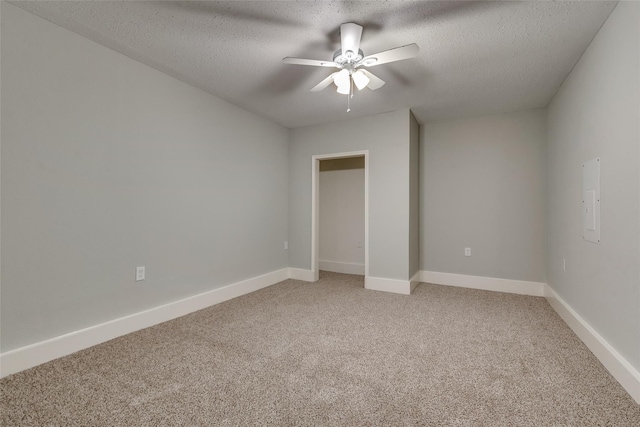 unfurnished bedroom with light carpet, a textured ceiling, baseboards, and ceiling fan