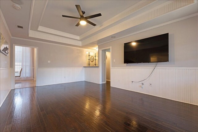 unfurnished living room with visible vents, ceiling fan, hardwood / wood-style flooring, wainscoting, and a raised ceiling