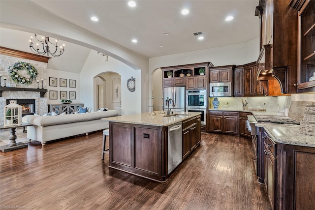 kitchen with open floor plan, dark brown cabinets, arched walkways, and stainless steel appliances