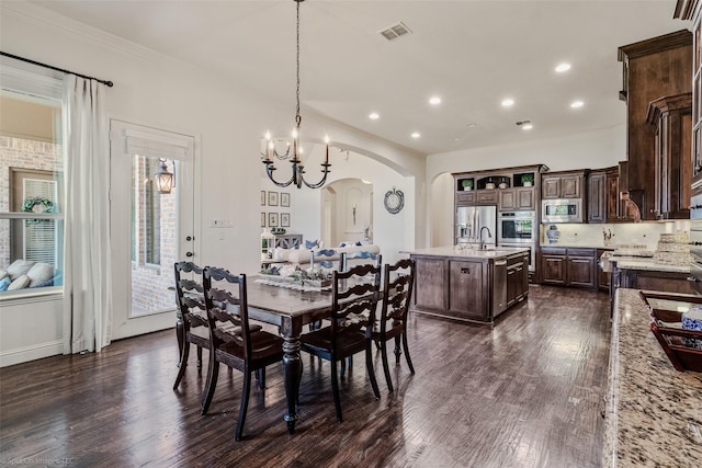 dining space featuring visible vents, arched walkways, dark wood-style floors, and ornamental molding