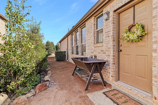 view of exterior entry featuring brick siding