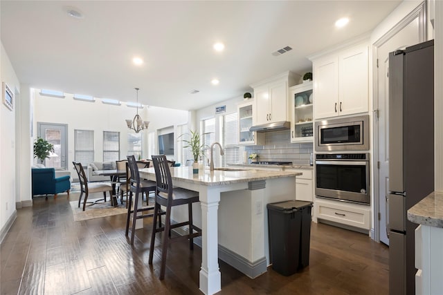 kitchen featuring visible vents, backsplash, under cabinet range hood, stainless steel appliances, and a sink