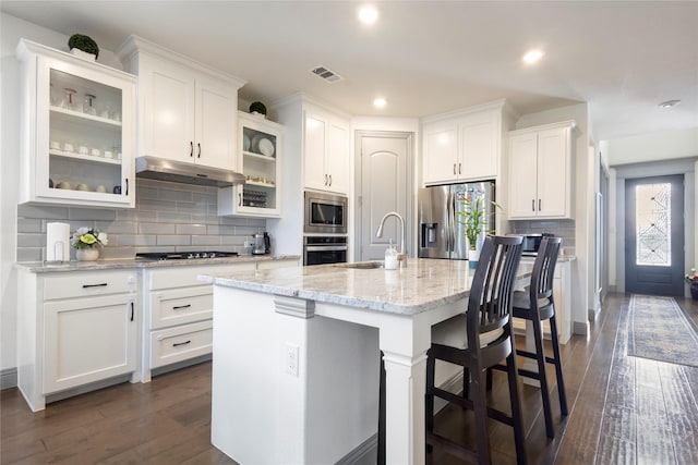 kitchen featuring under cabinet range hood, a sink, stainless steel appliances, white cabinets, and dark wood-style flooring