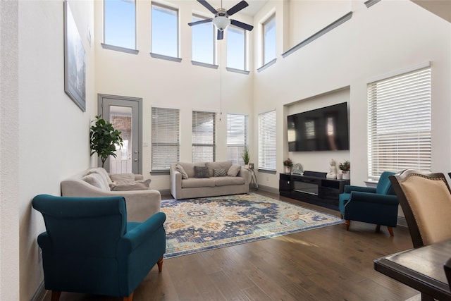 living area with a ceiling fan, baseboards, and wood-type flooring