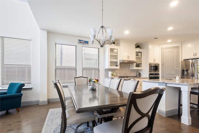 dining room featuring an inviting chandelier, recessed lighting, dark wood-type flooring, and baseboards