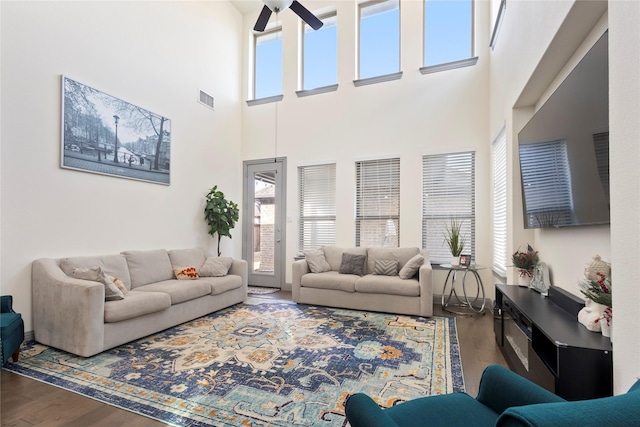 living room with a ceiling fan, wood finished floors, visible vents, and a wealth of natural light