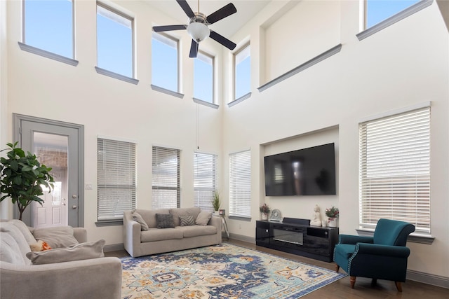 living area with baseboards, wood finished floors, and a ceiling fan