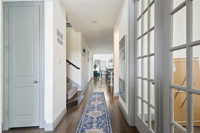 corridor with dark wood finished floors, stairs, and baseboards