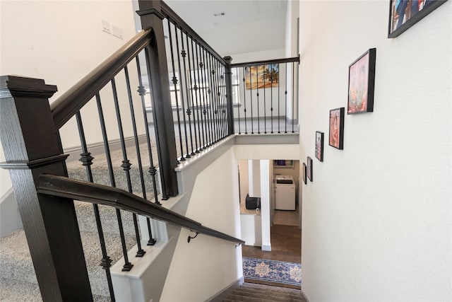 staircase featuring plenty of natural light, washer / dryer, a towering ceiling, and wood finished floors