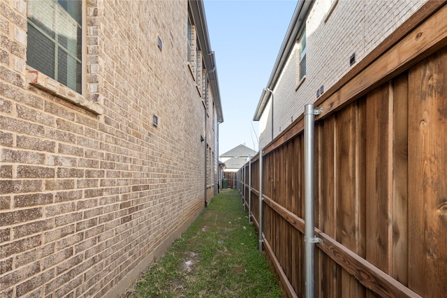 view of side of property featuring brick siding and fence