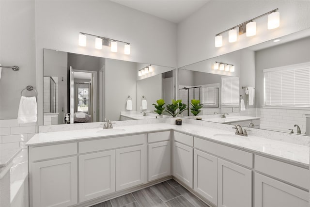 ensuite bathroom featuring double vanity, a shower stall, connected bathroom, and a sink