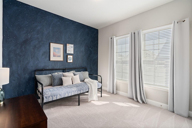 carpeted bedroom featuring an accent wall and baseboards