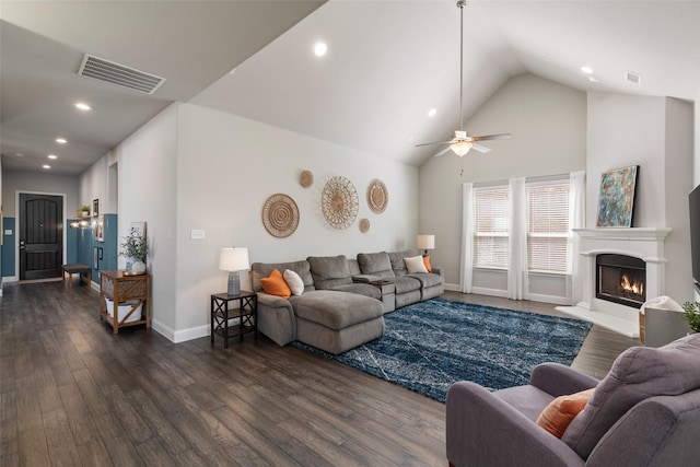 living area featuring dark wood finished floors, visible vents, a lit fireplace, and ceiling fan