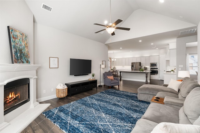 living area with dark wood finished floors, visible vents, high vaulted ceiling, and a ceiling fan