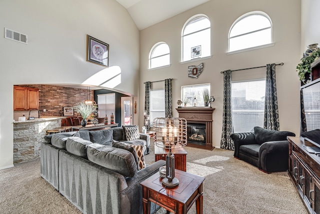 living room featuring visible vents, plenty of natural light, light carpet, and a glass covered fireplace