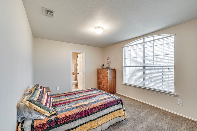 carpeted bedroom featuring connected bathroom, baseboards, visible vents, and a textured ceiling