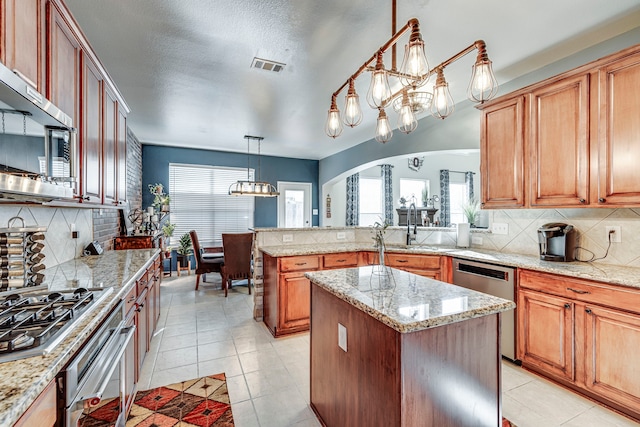 kitchen featuring backsplash, light tile patterned floors, appliances with stainless steel finishes, arched walkways, and a sink