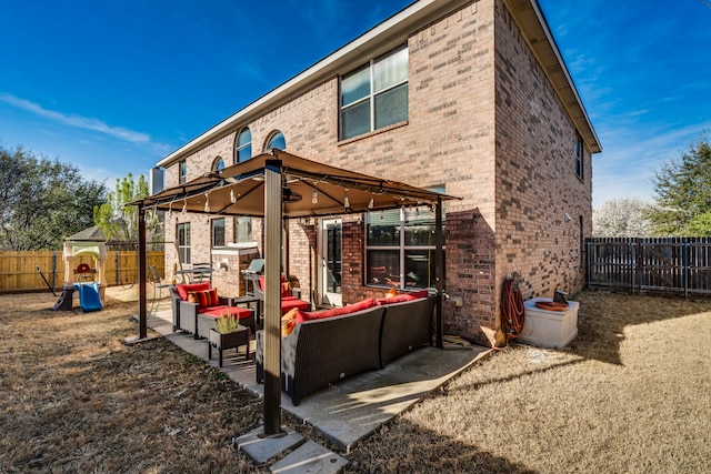 back of property featuring a fenced backyard, a gazebo, an outdoor hangout area, brick siding, and a patio area